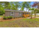 Attractive single-story brick home featuring a modern wooden porch railing and verdant lawn at 411 Berkeley Dr, Moncks Corner, SC 29461