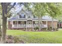 Stately two-story home with a wraparound porch, featuring classic architectural details and a neatly landscaped front yard at 4217 Meadowbrook Ct, North Charleston, SC 29420