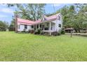 Lovely farmhouse with red metal roof, expansive lawn, and inviting front porch at 516 Hope Plantation Ln, Jacksonboro, SC 29452