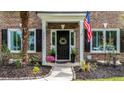 Inviting entryway featuring a black front door with wreath, flanked by plants and American flag at 555 Pointe Of Oaks Rd, Summerville, SC 29485