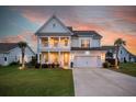 Charming two-story home with a double front porch, a well-manicured lawn, and a two-car garage at 682 Pontoon Rd, Huger, SC 29450