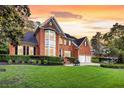 Beautiful two-story brick home with manicured lawn, mature trees and two-car garage at dusk at 8662 W Fairway Woods Dr, North Charleston, SC 29420