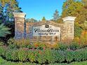 Community entrance sign for Posaw Creek Country Club with brick pillars and colorful flower bed at 8662 W Fairway Woods Dr, North Charleston, SC 29420