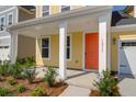 Close-up of a home's orange front door with white columns and manicured landscaping at 1217 Homecoming Blvd # Cc2-1-26, Ravenel, SC 29470