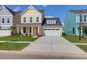 Beautiful yellow two-story home with a manicured lawn, white garage door, and bright orange front door at 1217 Homecoming Blvd # Cc2-1-26, Ravenel, SC 29470