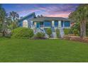 Inviting home with blue siding, complemented by a lush green lawn and manicured shrubbery at 13 32Nd Ave, Isle of Palms, SC 29451