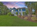 Charming elevated home with blue siding, a well-maintained lawn, and established landscaping at 13 32Nd Ave, Isle of Palms, SC 29451