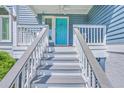 Close up of the home's front porch with a teal door and well-kept gray stairs at 13 32Nd Ave, Isle of Palms, SC 29451