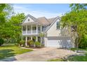 Two-story home featuring a front porch, two-car garage, and a basketball hoop, all surrounded by lush greenery at 2184 Tall Grass Cir, Mount Pleasant, SC 29466