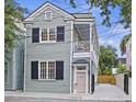 Two-story home with black shutters, a covered porch, and gated driveway at 29 Bogard St, Charleston, SC 29403