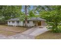Single-story white brick home featuring an attached carport, mature trees, and well-maintained landscaping at 4924 France Ave, North Charleston, SC 29405