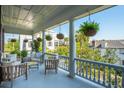 Covered porch with outdoor seating, white columns, and hanging fern plants at 5 Legare St # C, Charleston, SC 29401