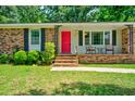 Close up of the brick home featuring a red door, front porch, and green lawn at 7 Azalea Ct, Goose Creek, SC 29445