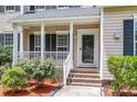 Inviting front porch with white railings, decorative bushes, and a glass front door at 8166 Scottswood Dr, North Charleston, SC 29418