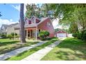 View of a charming red home, showcasing the driveway and a detached garage at 8965 N Red Maple Cir, Summerville, SC 29485