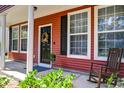 Inviting front porch with rocking chair and decorative wreath on the red front door at 8965 N Red Maple Cir, Summerville, SC 29485