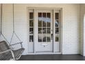 Close-up of the front door with glass panels and a classic design, complemented by a porch swing at 9 Wesley Dr, Charleston, SC 29407