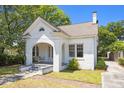 Quaint white brick home featuring a welcoming arched porch with swing and lush lawn at 9 Wesley Dr, Charleston, SC 29407
