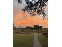 A picturesque backyard featuring a lush green lawn, brick pathway, and a stunning sunset, perfect for outdoor enjoyment at 932 N Shem Dr, Mount Pleasant, SC 29464