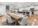 Open kitchen and dining area with island seating, stainless appliances, modern pendant lights, and light hardwood flooring at 1055 Royalist Rd, Mount Pleasant, SC 29464