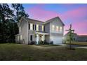 Charming two-story home with black shutters, manicured lawn and attached two car garage at dusk at 1132 Wading Point Blvd, Huger, SC 29450