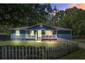 Charming blue home with a white picket fence and front porch at dusk at 116 Cone Ln, Summerville, SC 29483