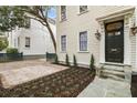 Charming house featuring cream siding, black trim, a brick driveway, manicured garden, and a covered front entrance at 19 Smith St # B, Charleston, SC 29401