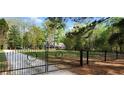 View of the front gate leading to a house, showcasing its secure entrance and the lush greenery of the property at 206 Chaussee Blvd, Summerville, SC 29483