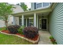 Inviting front porch with black door, white columns, shutters and vibrant landscaping at 3031 Ellington Dr, Summerville, SC 29485