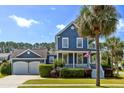 Beautiful blue home with a two-car garage, lovely landscaping, and a charming front porch with an American flag at 601 King Haven Ln, Johns Island, SC 29455