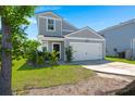 Charming gray home featuring green grass, lush foliage, and a pristine two-car garage at 630 Jancus St, Charleston, SC 29414