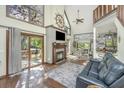 Open-concept living room features vaulted ceilings, wood floors, a cozy fireplace, and sliding doors to the outdoor deck at 2468 Marina Rd, Wadmalaw Island, SC 29487