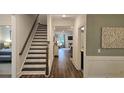 Hallway with hardwood floors, leading to stairs and a sunlit living area at 260 Huguenot Trl, Huger, SC 29450