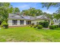 A charming single-story home adorned with solar panels, nestled among mature trees and a well-kept lawn at 4 Garth Dr, Charleston, SC 29414
