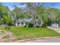 Inviting single-story home with a well-maintained lawn, mature trees, and solar panels installed on the roof at 4 Garth Dr, Charleston, SC 29414