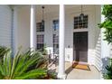 Inviting front porch with stately columns, a cozy seating area, and views of lush greenery at 7302 Sanderling Ct, Hanahan, SC 29410