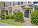 Close-up of the front entrance with a black door, lush bushes, and a small covered porch at 9010 Maple Grove Dr, Summerville, SC 29485