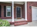 Close-up of a brick home's inviting front entrance featuring a black door, white columns, and a welcome mat at 116 Venezia Ct, Ladson, SC 29456