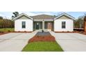 Charming exterior view of a duplex featuring a well-manicured lawn and double driveway at 117 Mims Academy Dr, Harleyville, SC 29448
