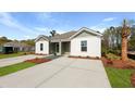 Charming exterior view of a duplex featuring a well-manicured lawn and a long driveway at 117 Mims Academy Dr, Harleyville, SC 29448