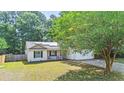 Charming single-story home featuring a cozy porch, two-car garage, and verdant lawn at 210 Basswood Ave, Summerville, SC 29483