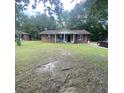 Wide shot of a brick home featuring a cozy front porch with inviting blue chairs and a manicured lawn at 214 Winter St, Moncks Corner, SC 29461