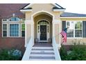 Stunning front entrance with stairs leading to a black front door, American flag, and brick facade at 2206 Magnolia Meadows Dr, Mount Pleasant, SC 29464