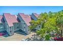 View of the condo building with metal roofs, showing assigned parking, mature trees, and coastal charm at 221 E Mariners Cay # 221, Folly Beach, SC 29439