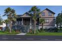 Charming home exterior with mature palm trees, lush landscaping, and a welcoming front porch at 27 Rebellion Rd, Charleston, SC 29407