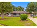 Charming brick home with well-maintained landscaping, mature trees, and a welcoming front porch at 4965 Foxwood Dr, North Charleston, SC 29418