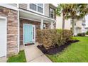 Close-up of the home's light blue front door, stone facade, manicured shrubs, and green lawn at 228 Donatella Dr, Goose Creek, SC 29445