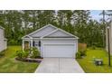 A cozy gray home boasts a one-car garage, complemented by lush landscaping against a backdrop of towering trees at 444 Cedarview Rd, Summerville, SC 29486