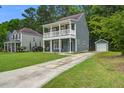 Front exterior of a charming home with double porches, well-manicured lawn, and mature trees at 4818 Buttercup Way, Summerville, SC 29485