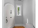 Entryway features a charming arched door, transom window, light walls, and light hardwood flooring at 7 Wesley Dr, Charleston, SC 29407